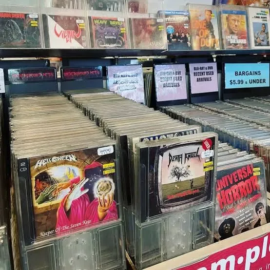 Compact discs in a record store bin, with Helloween and Death Angel albums in front and underground metal dividers above.